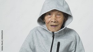 Senior Asian man wearing a hoodie sweater or cold weather zip sweatshirt. A 95 years old guy with a cataract eye problem with a gray cool shirt.