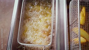 Crackling Potato. Preparation of a Potato Fries in a Deep Fryer at Restaurant of a Fast Food, the Concept of Unhealthy Food, the Top View Close Up.