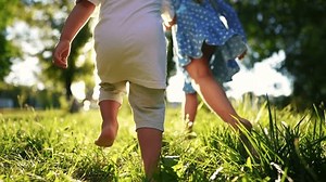children in the park. bare feet close up a children running. happy family kid dream concept. children hold hands run through the woods in the park with bare feet. happy family lifestyle concept