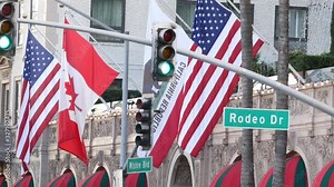 World famous Rodeo Drive Street Road Sign in Beverly Hills against American Unated States flag. Los Angeles, California, USA. Rich wealthy life consumerism, Luxury brands, high-class stores concept