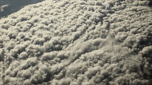 Aerial, view of planet earth from airplane window. Looking down on puffy clouds over Atlantic ocean on earth from airplane flying above the earth in cinematic slow motion.