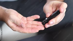 Men check their sugar levels using a lancet pen and glucometer