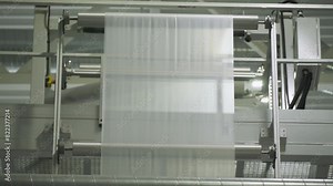 Plastic film processing at the industrial production plant. Stretching out the sheets of a plastic film for processing. Factory equipment processing the plastic film material. Recycling.