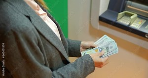 Business woman counting us dollars near ATM machine at night time