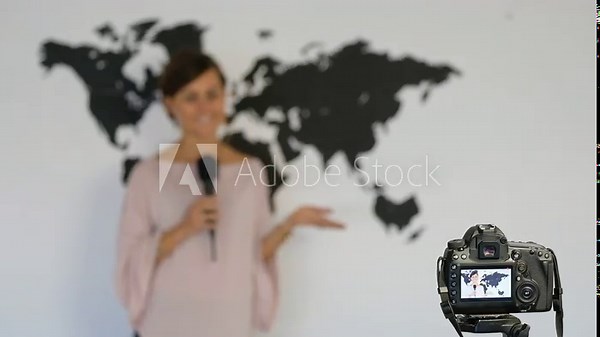Journalist reporting from the studio on the background of the world map in front of the camera. Focus to the cam