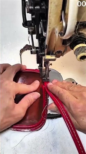 Red tool guides leather under machine, stitches bite into brown hide