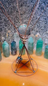 A miniature model of an energy coiled wire device in a pyramid vortex shape, containing a crystal ball and a pendulum. #frequency #vibration #relax #design #goodvibes #crystal #healingvibes #positivevibes | MineStone OnEarth
