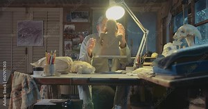 Old artist modeling a clay sculpture in a studio