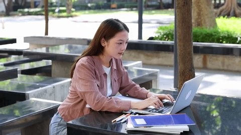 clip-3992250859-young-thai-woman-studies-outdoors-typing-on