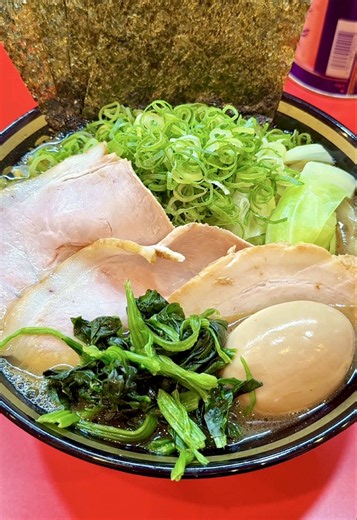 店内で炊く豚骨スープと自家製醤油の家系ラーメン！2種のチャーシューを盛った特製ラーメン 【横濱家系ラーメン十七代目野中家 八王子店】 東京都八王子市旭町にある「十七代目野中家 八王子店」へ撮影に伺いました。 2026年6月にオープン。大﨑家を創業した神田氏が手がける、横濱家系ラーメン「野中家」の八王子店です。 今回ご紹介するのは「特製ラーメン」。 店内で骨から炊いたスープに自家製醤油を合わせ、2種のチャーシュー（燻製、煮豚）、海苔、ネギ、キャベツ、ほうれん草を盛り付けた一杯です。 スープは豚骨と鶏油が香り、クセは強すぎず、醤油の塩気と骨の旨味を感じます。 特注の麺は平打ち風の中太ストレート。濃厚なスープがよく絡みます。 スープを含んだ海苔は、麺と一緒に食べても、ライスと合わせても楽しめます。 食券を渡すときに、麺の硬さ・味の濃さ・脂の量を聞いてくれます。 卓上にはマヨネーズ、ふりかけ、極ニンニク、極ショウガ、豆板醤、ニンニクなどが並びます。 きゅうりの漬物と角切りチャーシューを合わせた「裏ガッパ」もライスのお供に人気です。 JR八王子駅北口から徒歩約3分。駅のすぐ近くで家系ラーメンを食
