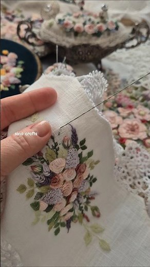 Small floral rococo hand embroidery design on white linen cloth decorated with needle tatting lace.