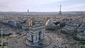 Triumphal arch or Arc de Triomphe and car traffic on roundabout with Tour Eiffel in background, France. Aerial orbiting