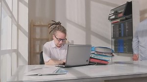 Female office worker sleeps at workplace during working day. Serious angry boss loads sleeping employee with overtime by throwing bunch of folders on table, woman wakes up.