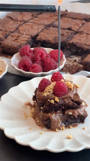 Nyårsbakelse - fudge brownies med nutellafluff. Perfekta att servera och blir extra festliga med tomtebloss på toppen. Ingredienser brownie: 200 g mörk choklad 200 g mjölkchoklad 175 g smör 4 ägg 3 dl strösocker 2,5 tsk vaniljsocker 1.8 dl vetemjöl 5 msk kakao 0.5 tsk flingsalt Nutellafluff 3 dl grädde 200 g nutella Övrigt: Hallon Saltade jordnötter eller hasselnötter Gör så här: 1. Fluff: Värm grädden i en kastrull, OBS! den får inte koka. Blanda i rumstempererad nutella och rör tills all nutel
