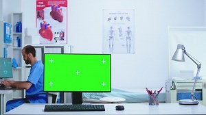 Monitor in hospital cabinet with chroma key while doctor and nurse checking x-ray image. Desktop with replaceable screen in medical clinic while doctor is checking patient radiography for diagnose.