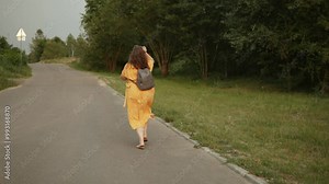 Plus size woman running away from natural hazard before summer storm on road, tracking shot. Female person looks back, leaves flying from trees on cloudy day.