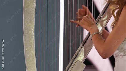 Harpist performing close up, hands plucking strings of glittering musical instrument