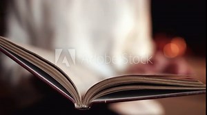 Woman flipping through pages of paper book. Lady with novel. Girl sitting home near fireplace and looking for information from old literature.