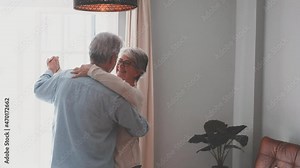 Happy and funny couple of old and mature people having fun and enjoying at home doing a party together singing and dancing playing the guitar indoor. Holiday or event celebrating concept.
