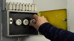 Replace a ceramic fuse in old fuse box. An open fuse box where an older ceramic fuse is screwed in where one is missing. An electrically hazardous light flash is visible when the fuse is screwed in. A