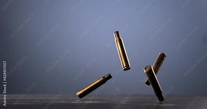 SUPER SLOW MOTION Empty machine gun shells falling on a ground against blue background. Shot with high speed camera at 420 FPS