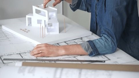 clip-3992659053-architect-sketching-building-plans-on-paper-using