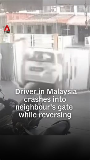 A driver reversing out of a home in Malaysia is believed to have pressed the accelerator too hard, sending his car crashing into a neighbour’s gate and causing it to collapse. No one was hurt, but the viral clip sparked concern online about the danger it could have posed to passers-by. | CNA
