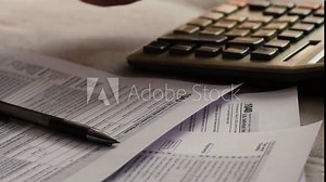 concept calculation and payment of taxes of a US citizen, tax form 1040 on the table, pen and hand counting on a push-button calculator, tax deductions filling out a declaration