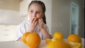 girl child eating oranges. happy family fruit healthy food kid concept. little girl daughter eating oranges at the table in the kitchen indoors. dream juicy fruits oranges are for a healthy diet