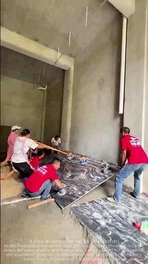 The process of laying large marble tiles with the assistance of multiple people.