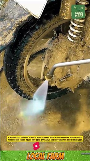 A motorcycle covered in mud is being cleaned with a high-pressure water spray.