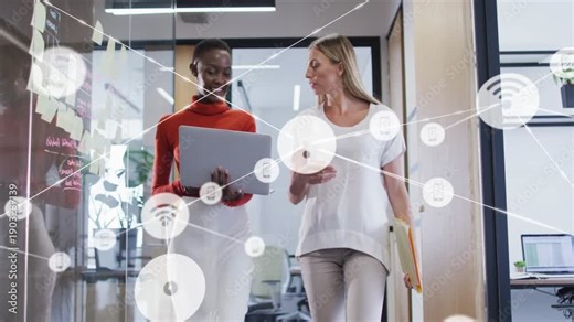 Two business women walking hall tilting laptop causing network overlay annotating data resuming