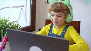 Schoolboy child using laptop and headphones online educational lesson course at home. Distance learning remote video conference. Schoolgirl study does school homework. Child call with relatives friend