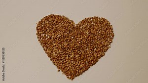 A heart made of buckwheat. The camera smoothly moves into a closer shot, allowing us to see the texture of the buckwheat grains and their natural beauty.