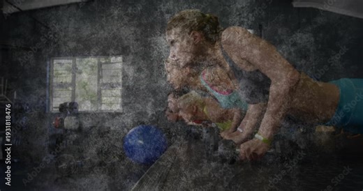 Lead female doing dumbbell pushups for strength in gym following trainer cue, grain obscuring faces