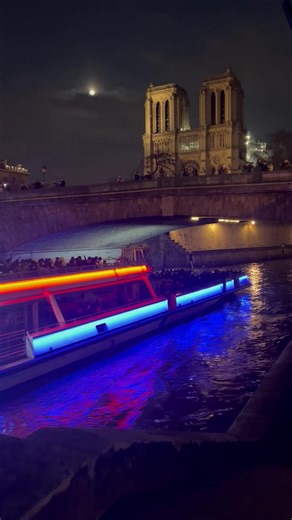 The Bateaux Mouches moved smoothly along the Seine, its lights shining on the water. Tourists crowded along the railings, excited and ready with their cameras. As the boat turned, they saw it—Notre Dame, standing tall and beautiful, its towers reaching up to the night sky. The crowd cheered and clapped, their faces lit up with joy. Some gasped, others pointed, trying to take the perfect photo. But no picture could show how magical it felt to see it in real life. Golden lights shone on the old st