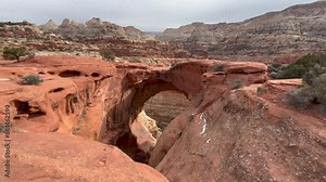 Red rock formations and the natural arch of iconic Cassidy Arch at Capitol Reef National Park in Utah. Wider view highlighting the height of the arch and deep canyon below - USA