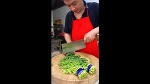Chopping bundled green beans with cleaver on wooden board creating perfect even pieces