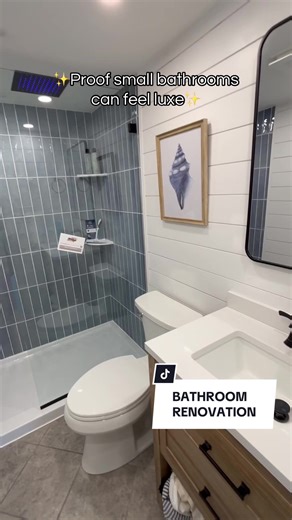 Small bathroom, major glow-up! A walk-in glass shower with soft blue vertical tile, matte black fixtures, and a spa-style rain shower instantly elevates the space. Shiplap walls keep it bright, while the warm wood vanity adds contrast and storage. Simple, timeless, and hotel-level cozy. #bathroomrenovation #rainshower #bathroomremodel #homerenovation #coastalvibes