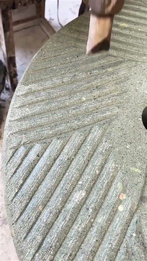 rotating a traditional millstone for grinding grains by hand using a wooden handle and stone surface