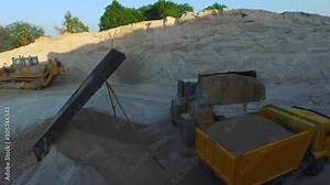 Grader scraper load grit material into the truck in canyon Drone 4K footage