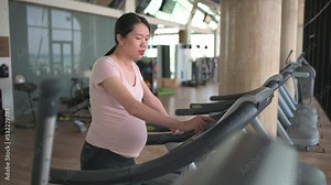 Pregnant woman exercising in the gym indoors walking on a treadmill for a fit and active lifestyle during pregnancy