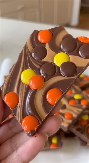 3-Ingredient Reese's Pieces Bark Easy Peanut Butter Chocolate Candy Shard Ingredients: 12 oz Milk chocolate (340 g) 1/2 cup Creamy peanut butter (125 g) 1 cup Reese's Pieces candies (200 g) Directions: 1. Line a baking sheet with parchment paper. 2. Melt the milk chocolate and pour it onto the prepared tray, spreading it into an even layer. 3. Melt the peanut butter until pourable and drop dollops over the wet chocolate. 4. Use a knife or spatula to swirl the peanut butter into the chocolate. 5.