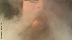 close up of smoke from nose young bearded handsome man with mustache and beard smokes and releases thick tobacco smoke from his mouth into the nostrils of his nose, out cigarette smoke up his nose