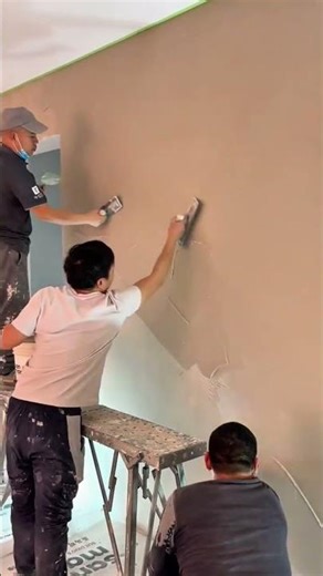 A person is plastering wall using cement manually