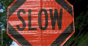 Road Construction Flagger Turning Sign from Stop to Slow While Directing Traffic
