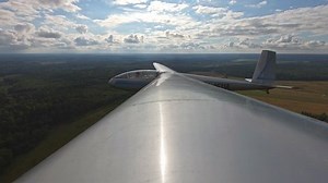 POV view feom wing beautiful glider soars in blue sky and flies forward with currents of wind. unpowered aircraft is piloted at high altitude.