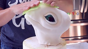 3.7K views · 105 reactions | Learn to make a fun sculpted dinosaur egg cake using simple cake structure techniques. The dinosaur topper made from rice cereal and isomalt eyes and watercolor scales can be made ahead of time and placed on top of the egg cake before setting up. https://sugargeekshow.com/free-video/dinosaur-egg-cake-tutorial/ | Sugar Geek Show | Facebook