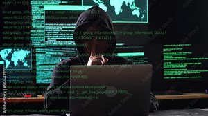 Asian Male Hacker In A Hood Showing Shh Gesture While Works On A Laptop With Maps And Data On Display Screens Of Multiple Monitors In A Dark Office Room. Code Animation Footage