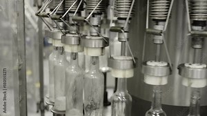 Operation of an automatic bottle filling machine with liquid. Movement, fixing and filling bottles close-up shot. Stock Video